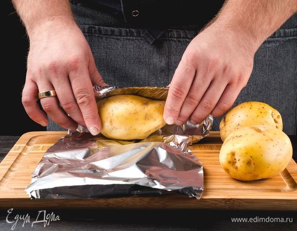 Промойте картофель, плотно оберните фольгой и отправьте выпекаться в разогретую до 180°C духовку на 1 час.