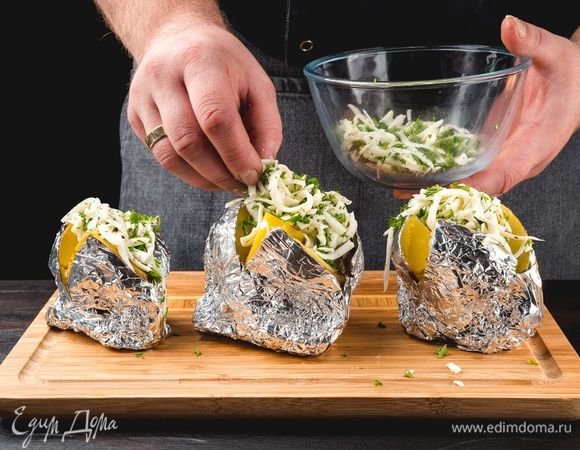 Внутрь картофеля добавьте сливочное масло, посыпьте сыром с зеленью. Отправьте в духовку еще на 10 минут.