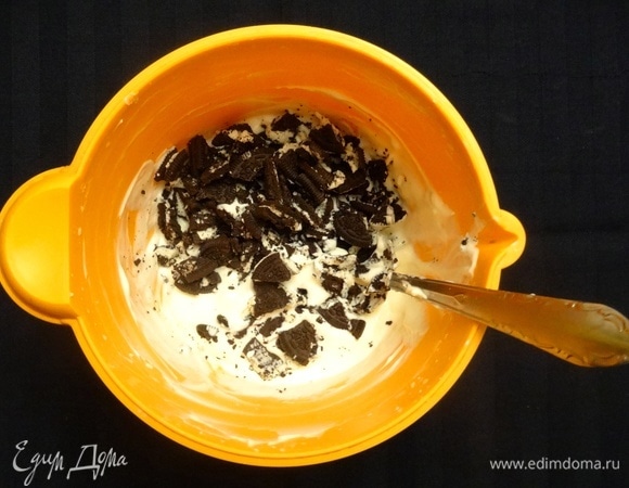 Половину крема убрать в холодильник. В остальную массу покрошить руками печенье и перемешать. Часть печенья (4–5 шт.) оставить для украшения торта.