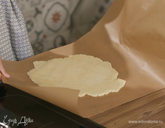 Вымесить тесто руками и сделать из него шар, выложить его между двумя листами для выпечки и раскатать в пласт.