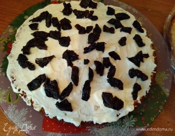 Сверху крема выложить половину чернослива. Сверху положить еще один корж, затем — крем, чернослив, корж и снова крем. Бока смазать оставшимся кремом.