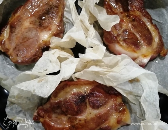 На противень кладем листы пергаментной бумаги и выкладываем на нее свинину.
