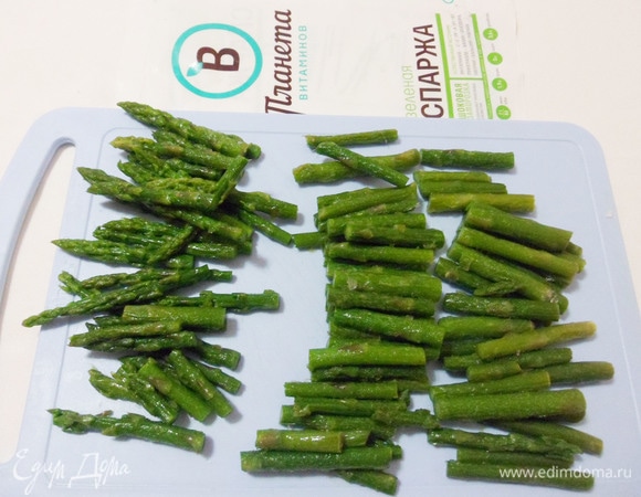 Спаржу полностью размораживать не нужно, дадим ей немного оттаять и нарежем кусочками. Горсть верхних частей побегов спаржи отложим в сторону.