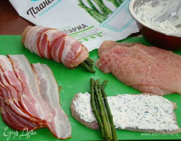 Куриное филе смазать сливочным сыром. Уложить с одного края пучок спаржи и, свернув в рулет, обмотать пластинками бекона.