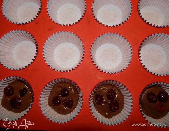 В формы для кексов вложить бумажные капсулы, выложить по 1 ст. л. теста, положить по 3 ягодки и доложить тесто, заполнив форму на 3/4. Выпекать кексы в разогретой до 180°C духовке 20–25 минут.