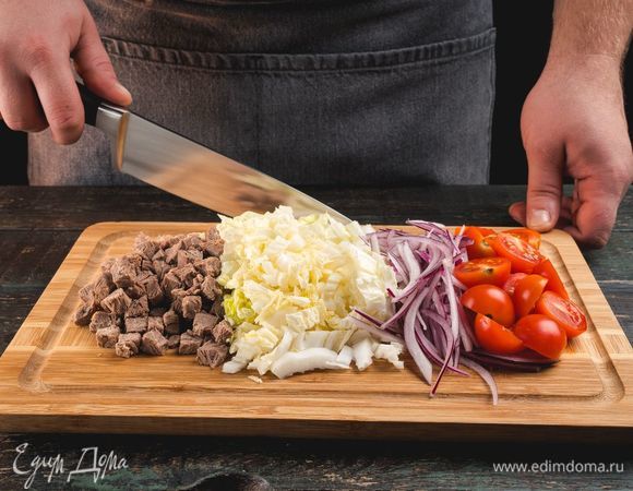 Говядину отварите и нарежьте кубиками, лук очистите и также нарежьте кубиками. Выньте сердцевину из помидоров и нарежьте их дольками. Китайскую капусту нарежьте соломкой.