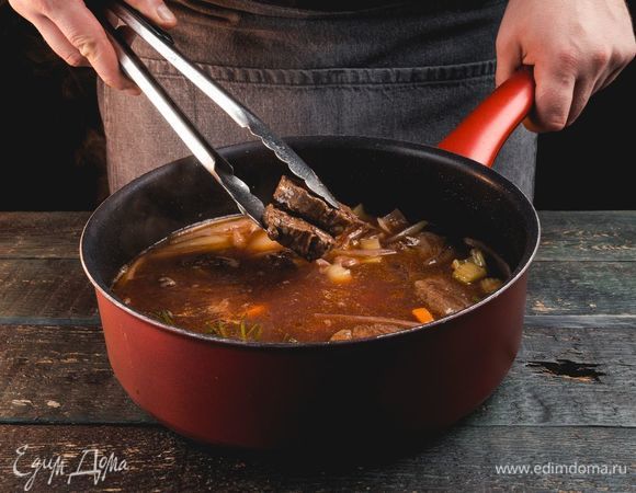 Тушите, пока жидкость не уменьшится вдвое. Затем влейте бульон, доведите до кипения и добавьте мясо. Варите 2–2,5 часа.