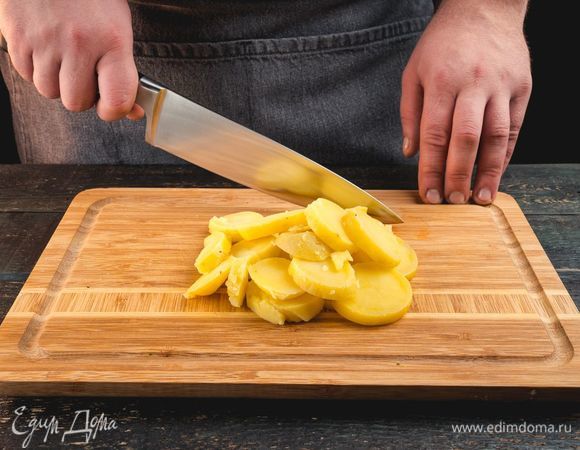 Картофель помойте и отварите. Остудите, нарежьте кружочками.