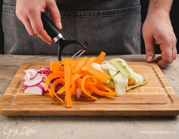 Морковь и огурцы очистите, нарежьте слайсами при помощи овощерезки. Редис нарежте тонкими полукольцами.