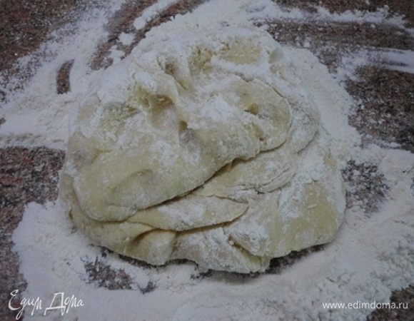 Половину муки смешиваем с содой и солью и добавляем к масляной смеси, замешиваем ложкой. Остальную муку высыпаем на стол, выкладываем на нее тесто и уже руками продолжаем вымешивать, но не слишком долго. Тесто не пристает к рукам и стало мягким — все, достаточно. Остатки муки я взвесила — 90 г. Из этого количества я взяла муку для раскатки. Примерно одну треть теста отделите для верха и уберите в холодильник.