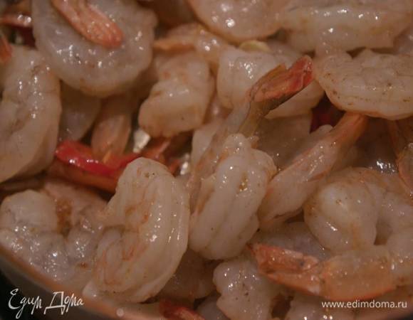 Вернуть сковороду на огонь, влить 2 ст. ложки оливкового масла, выложить чеснок, чили и натертый имбирь, всыпать зиру, сухой имбирь, корицу, мускатный орех, все перемешать и посолить, затем добавить креветки и обжаривать, пока они не станут бледно-розовыми.