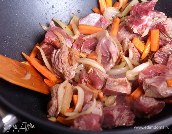 Следом добавить морковь, жарить еще 5 минут. Добавить мясо и специи, жарить 5 минут, пока мясо не станет матовым.