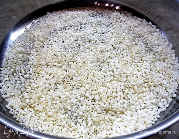 В глубокую сковороду наливаем 3 ст. л. оливкового масла, высыпаем рис и обжариваем его на среднем огне, помешивая, 2 минуты. По краям рис станет прозрачным, а в середине — белым.