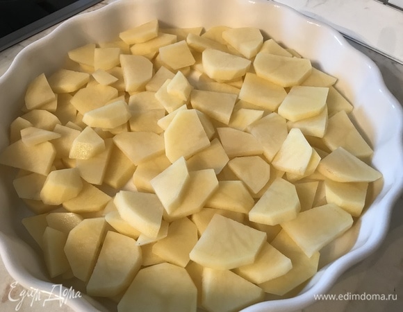 Очищаем картофель и режем плоскими сегментами. Немного подсаливаем и выкладываем в форму для запекания.