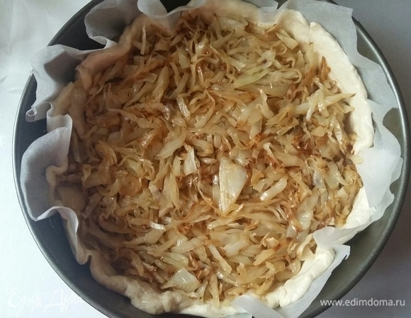 Взять разъемную форму (у меня диаметром 22 см). Застелить пергаментом. Выложить тесто, сформировав бортики руками. На тесто выложить начинку из капусты.