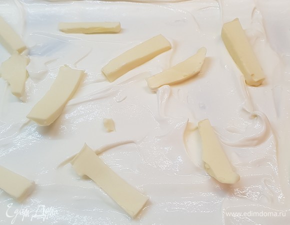 Духовку разогреть до 200°C. На дно формы для запекания выложить половину сметаны. Разложить кусочки сливочного масла.
