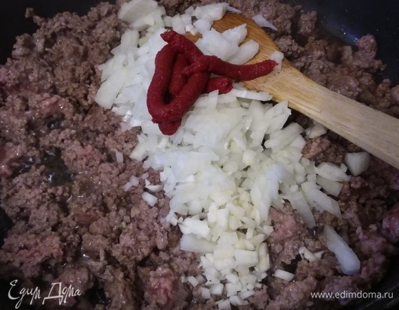 Чтобы приготовить соус, нужно разогреть масло и обжарить фарш в течение 5–6 минут. Добавить мелкорубленый лук, чеснок и томатную пасту, обжарить еще пару минут.