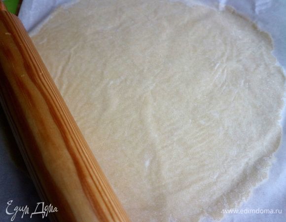 Форму слегка смазать сливочным маслом. Излишки масла убрать салфеткой. Раскатать скалкой тесто до нужного размера. Снять верхний слой пергамента, накрыть формой, перевернуть форму вместе с тестом. Снять второй лист пергамента.