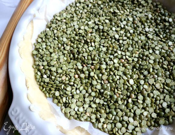 Положить на тесто в форме лист пергамента, горох или другой натуральный или искусственный наполнитель. Отправить в предварительно разогретую духовку на 15 минут.