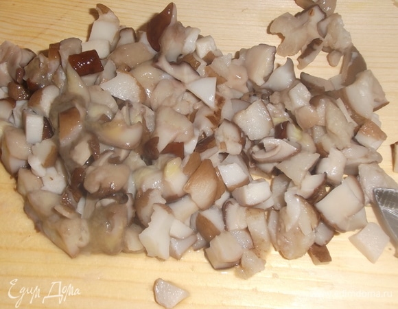 Перловку замочить в воде на 3 часа, затем воду слить, залить снова водой в пропорции 1:3 и варить на медленном огне 50 минут. В конце готовки крупы слить стакан отвара и отставить для начинки. Замороженные грибы отварить в воде с лавровым листом и душистым перцем. Слить, некрупно нарезать.