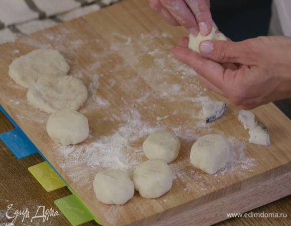 Сформировать из теста небольшие, тонкие лепешки, выложить на присыпанную оставшейся мукой доску, в центр каждой лепешки поместить кусочек сулугуни и слепить пышки.
