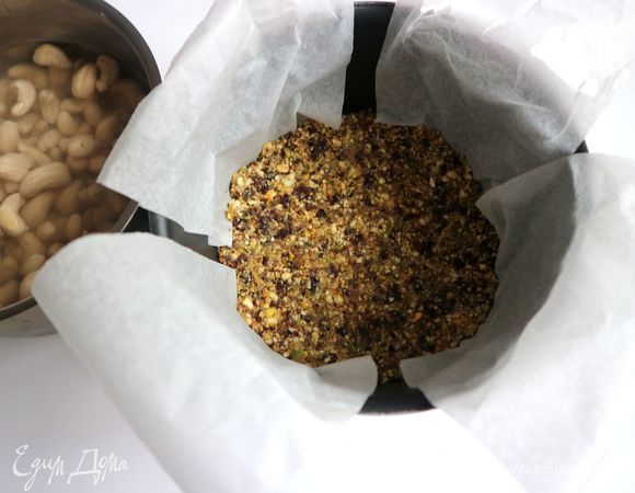 Форму застелить бумагой для выпечки таким образом, чтобы удобно было вынимать кешьюкейк после приготовления. Бумага должна немного выступать из формы. Положить слой смеси на бумагу, которой застелена форма. Утрамбовать, убрать в морозильник примерно часа на 1,5.