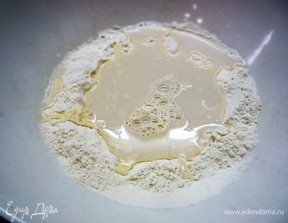 В центре муки делаем небольшое углубление и вливаем дрожжевую смесь. Сначала перемешиваем смесь вилкой, затем вымешиваем руками, при необходимости добавляем немножко муки.