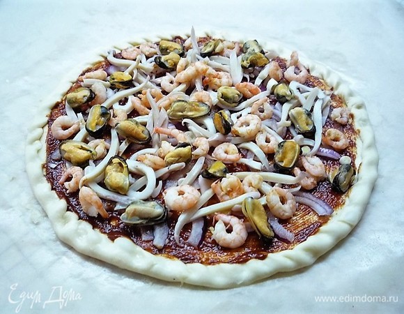 Поверх лука выкладываем нарезанного тонкими полосками кальмара, креветки и мидии. Посыпаем смесью итальянских трав и перцем.