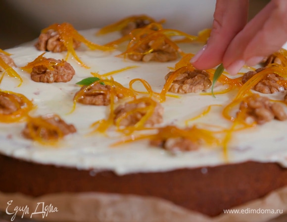 Остывший пирог смазать сливочным кремом, украсить половинками грецких орехов, апельсиновой карамелью и листьями базилика.