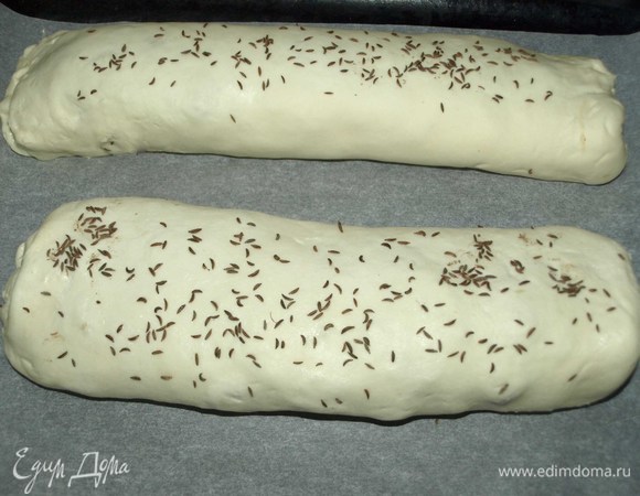 Рулеты сверху слегка смазать водой и посыпать тмином. Перекладываем на противень, застеленный пекарской бумагой, швом вниз.