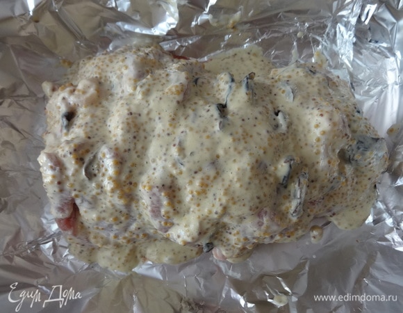 Подготовленный кусок мяса с черносливом выложить на фольгу. Обмазать со всех сторон смесью горчицы и майонеза со специями.