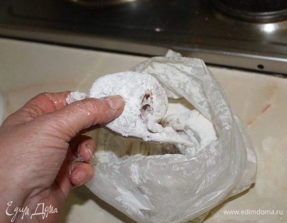 В сковороду налейте масло и поставьте на плиту. Пока масло достигает необходимой температуры, насыпьте в крепкий пакет муку. Положите в пакет с мукой необходимое количество рыбы, которое поместится на вашей сковороде, надуйте и закройте его. Аккуратно перемешайте в нем кусочки рыбы, чтобы каждый запанировался. Выложите на сковороду в горячее масло рыбу и жарьте на огне чуть выше среднего.