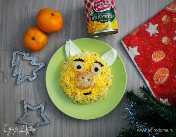 Выкладываем салат на общее блюдо или на порционные тарелки в форме полусферы. Сверху посыпаем салат натертым желтком, из отложенного белка делаем ушки, из хлебных кружочков — носик и глазки свинки, черными маслинами «прорисовываем» зрачки и ротик. Вот и все! Наша веселая желтая свинка готова! Приятного аппетита вам и вашим гостям!