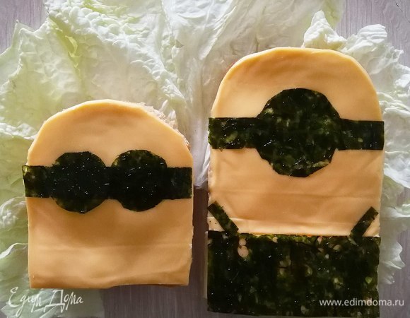 Укладываем сыр и листья нори, вырезанные по форме миньонов.