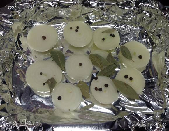 Противень небольшой выстилаем фольгой, выкладываем на дно лук, нарезанный крупными кольцами (для воздушной прослойки), высыпаем часть специй.