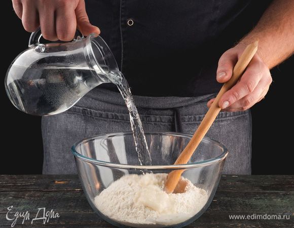 В большую миску просейте муку, добавьте стакан кипятка и соль.