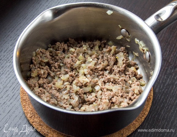 Добавить мелкорубленый чеснок и фарш. Лопаткой измельчить фарш. Обжаривать, пока он весь не поменяет цвет.