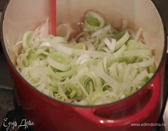 Светлую часть лука-порея нарезать тонкими кольцами, добавить в кастрюлю с репчатым луком.