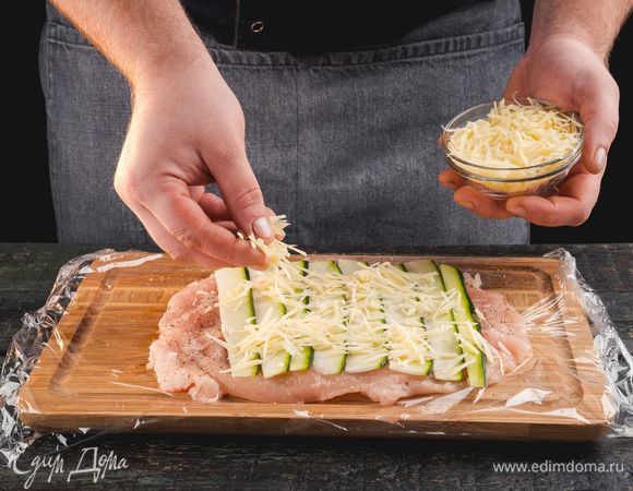 Куриное филе положите на пищевую пленку. На куриное филе выложите цукини. Посыпьте тертым сыром.