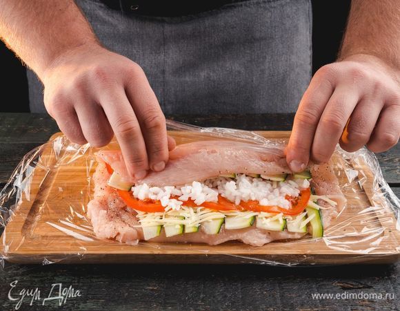 Выложите сверху рис тонким слоем. Аккуратно сверните курицу в рулет и скрепите зубочистками.