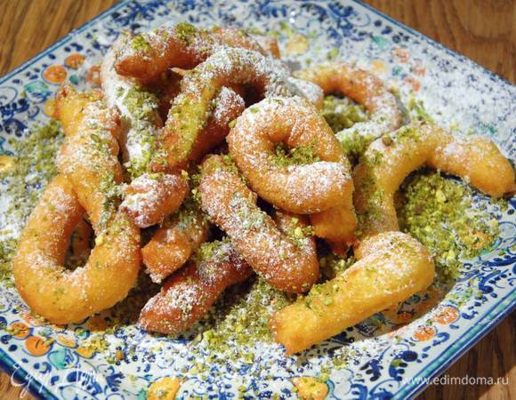 Готовые горячие пончики посыпать измельченными фисташками и сахарной пудрой.