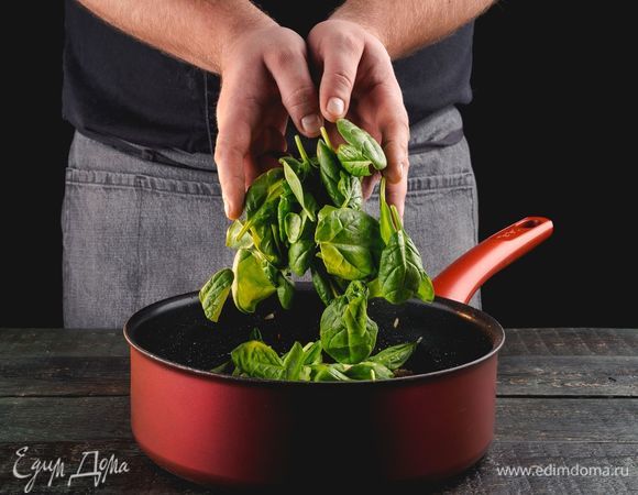 Сверху в сковороду выложите листья шпината, накройте крышкой и томите 2 минуты. Откройте крышку, полейте шпинат лимонным соком, перемешайте.