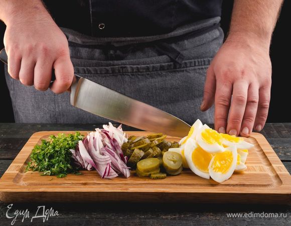 Лук нашинкуйте, яйца отварите, очистите и измельчите. Нарежьте огурцы и нашинкуйте петрушку.