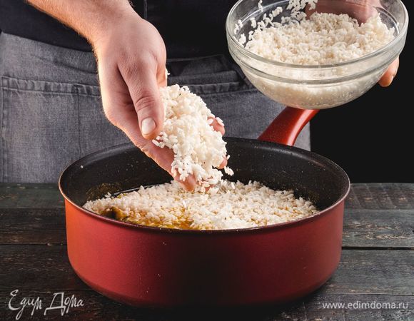 Добавьте рис. Варите 1,5 часа, не перемешивая, но периодически проводя лопаткой по стенкам сковороды, чтобы рис не пригорал.