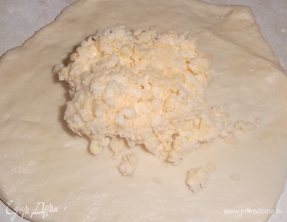 Каждую часть раскатать в небольшую лепешку. На середину выложить столовую ложку начинки.