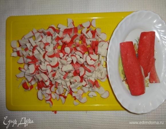 От двух крабовых палочек отрезать красные части для украшения. Остальные палочки мелко нарезать.