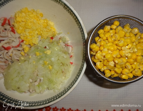 Слить жидкость с необходимого количества кукурузы. Одну чайную ложку кукурузы отложить. Подготовленные для салата продукты положить в чашку (кроме белков).