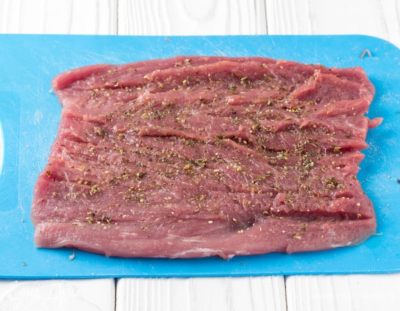 У свиной вырезки снять пленки и отрезать тонкий хвостик. С одного края начать разрезать филе по всей длине, раскрывая, как рулет, чтобы получился пласт толщиной примерно 1 см. Слегка отбить мясо, лучше не использовать грубые молотки, я несильно отбила просто кулаком, так как эта часть свинины очень нежная. Посолить, поперчить мясо и добавить итальянские сухие травы. Можно добавить буквально пару капель оливкового масла и дать мясу время немного замариноваться.