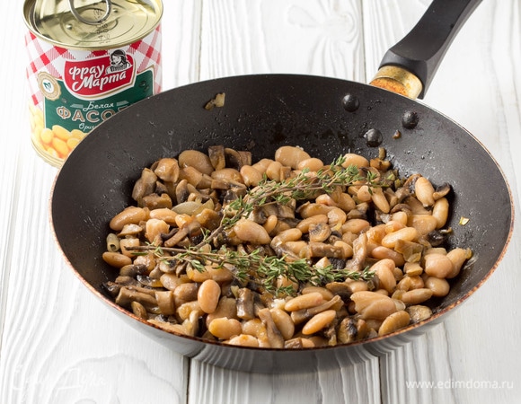 Шампиньоны нарезать кубиком и положить на разогретую сухую сковороду. Когда шампиньоны отдадут весь свой сок, добавить масло и мелконарезанную луковицу. Обжаривать все вместе на среднем огне 5–7 минут. Добавить фасоль ТМ «Фрау Марта», предварительно дав стечь соку, и несколько веточек свежего тимьяна, прогреть все вместе 5 минут на слабом огне.