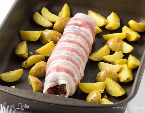 Рулет выложить в форму. У меня был отваренный картофель, я его тоже добавила в форму, сбрызнув маслом. Запекать 25–30 минут при 220°C. Затем включить гриль и оставить еще на 5 минут, чтобы бекон подрумянился.